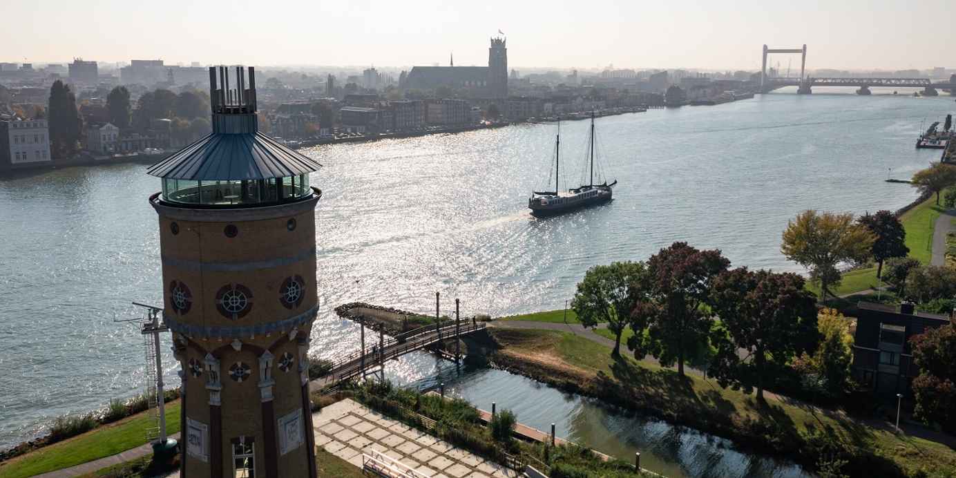 Luchtfoto van een kanaal met een silo, een schip en omringende huizen.